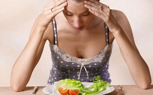 Young woman re-feed in eating disorder looking at plate of salad 