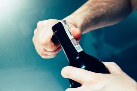 Man suffering from drunkorexia opening bottle of wine