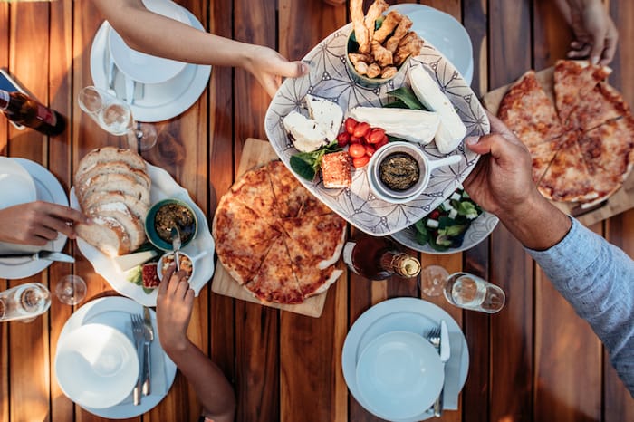 man passing plate of food at dinner table