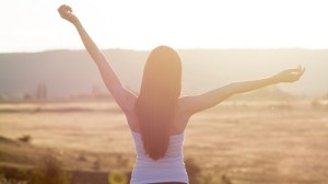 cheering woman open arms to sunrise