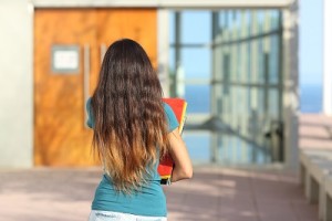 Back view of a teen girl walking towards the school