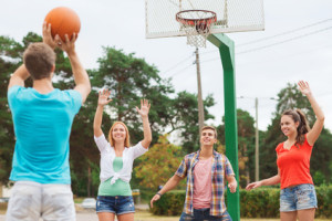 group of smiling teenagers playing basketball