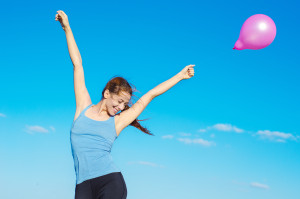 happy smiling woman arms raised with flying air balloon