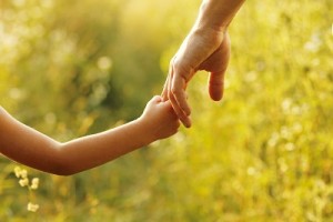 parent holds the hand of a small child