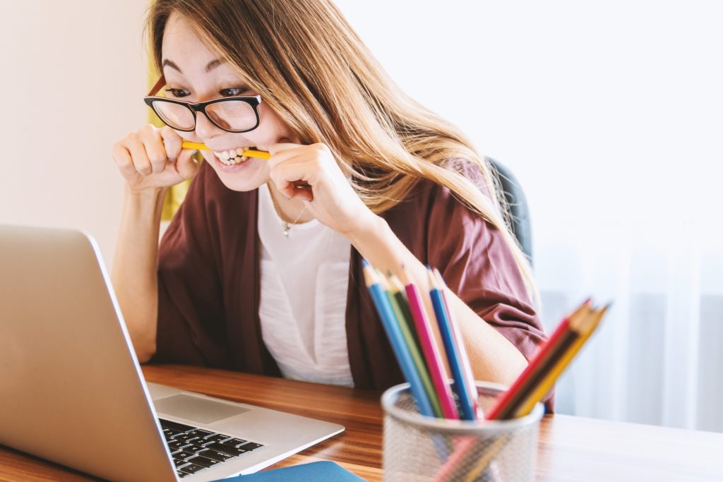 Woman looking at a computer while biting a pencil