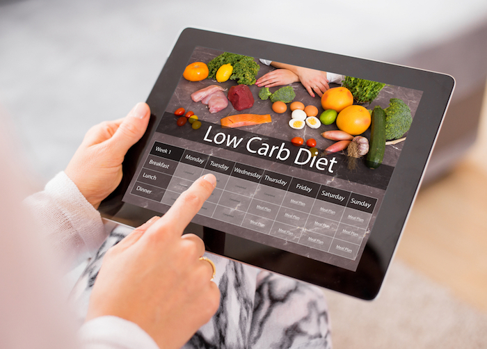 person holding tablet with low carb diet on screen