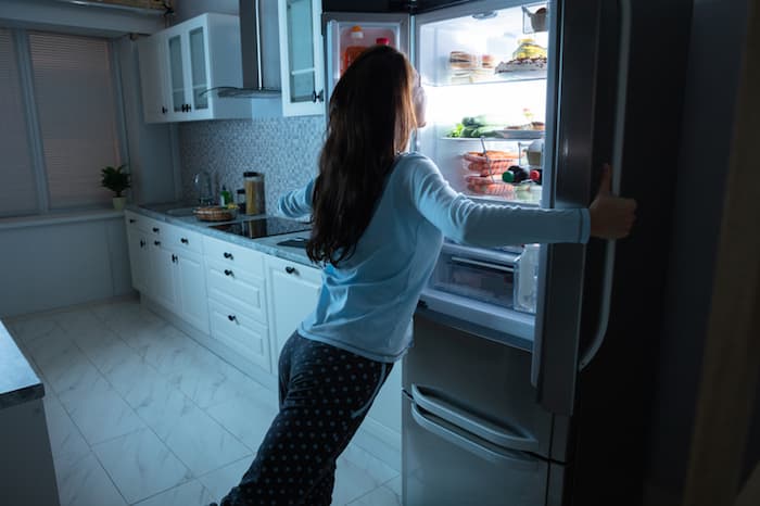 woman looking in refrigerator at night