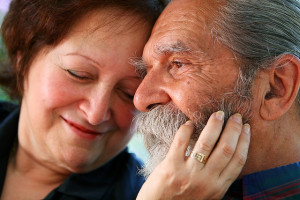 Affectionate old couple with the wife holding on lovingly to the husband's face. Focus on the husband's eyes. Concept: Elderly love.